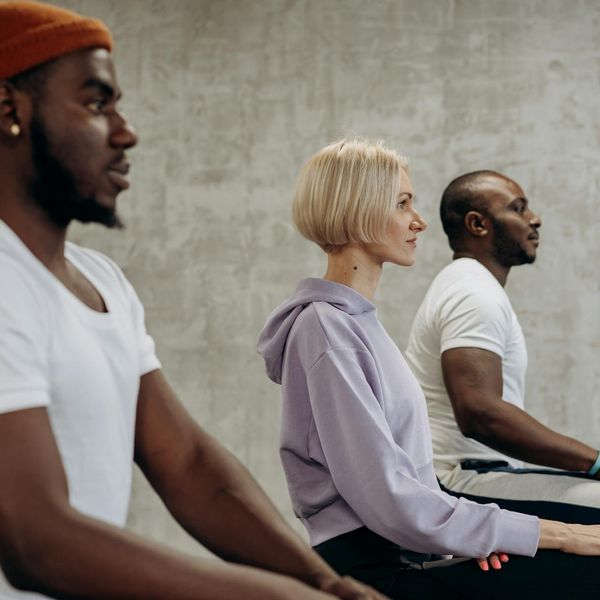 Group of diverse athletes stretching on yoga mats in a modern studio.