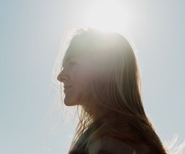Silhouette of a person meditating at sunrise, focusing on breath.